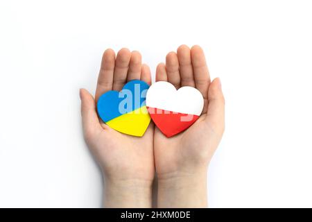 Les mains des enfants tiennent deux coeurs avec des drapeaux de l'ukraine et de la pologne sur fond blanc. Notion d'aide à la solidarité de l'unité Banque D'Images