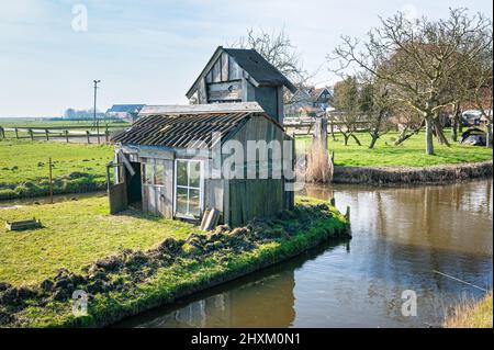 Ancien hangar en bois le long du bord de l'eau lors d'une journée de printemps ensoleillée Banque D'Images