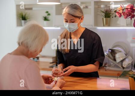 Médecin aidant la femme âgée à la maison Banque D'Images