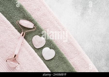 Outils de massage du visage. Massages Gua Sha et rouleau facial en quartz rose sur une serviette rose. Concept SPA. Vue de dessus, espace de copie pour le texte Banque D'Images