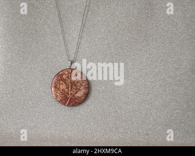 collier avec pendentif de texture de feuilles d'argile polymère fait main Banque D'Images