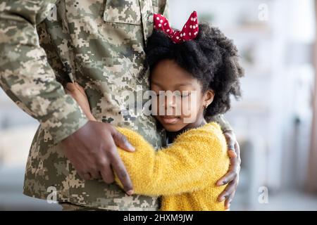 Gros plan de la petite fille africaine américaine câliner le père militaire en uniforme Banque D'Images