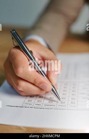 Cochez toutes les cases appropriées. Gros plan d'un homme remplissant un questionnaire médical. Banque D'Images