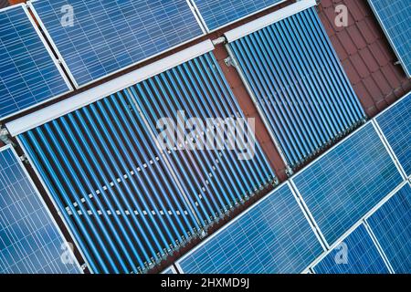 Toiture de bâtiment avec rangées de panneaux photovoltaïques bleus et capteurs solaires d'air sous vide pour le chauffage de l'eau et la production d'électricité écologique propre. Rene Banque D'Images