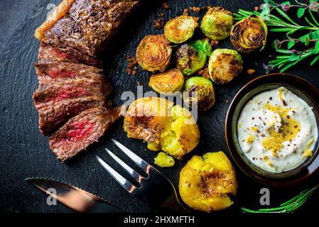 Couper le steak de type Wagyu moyen-rare avec des tomates rôties et des choux de bruxelles Banque D'Images