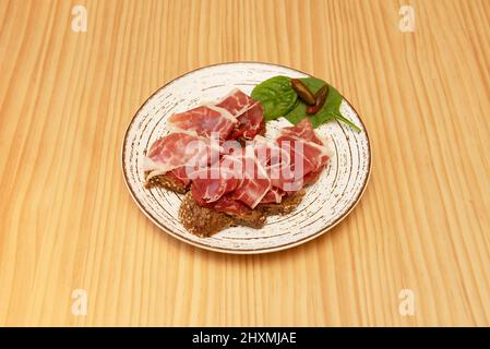 Pain grillé à l'ail avec tomate râpée, jambon ibérique et arugula, une idée très simple d'apéritif Banque D'Images