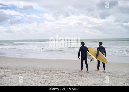 Surfer avec mon meilleur ami. Deux jeunes surfeurs sur la plage. Banque D'Images