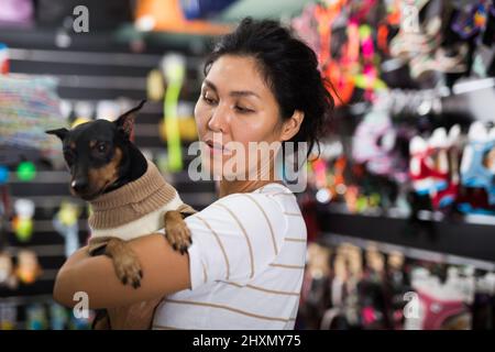 Femme orientale avec son petit chien dans la boutique d'animaux Banque D'Images