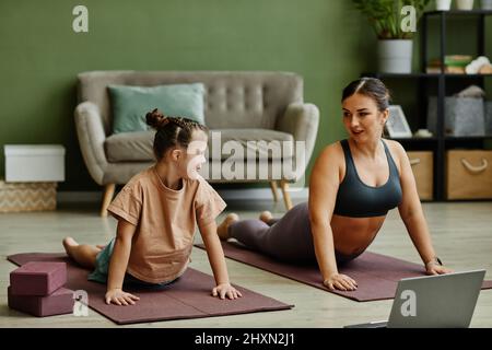 Portrait de la jeune fille avec le syndrome de Down appréciant l'entraînement à la maison avec l'aide d'un instructeur féminin Banque D'Images