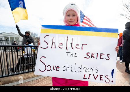 Washington, États-Unis. 13th mars 2022. Une jeune fille porte un panneau indiquant « Shelter the SKIES Save Children Lives ! » Lors d'un rassemblement en face de la Maison Blanche pour soutenir l'Ukraine. Crédit : SOPA Images Limited/Alamy Live News Banque D'Images