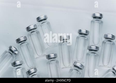 Flacon en ampoule médicale en verre pour injection. La médecine est un médicament blanc sec pénicilline poudre ou liquide avec de solution aqueuse dans l'ampulla. Gros plan. Flacons ampoule avec bouchon en aluminium sur fond gris. Banque D'Images