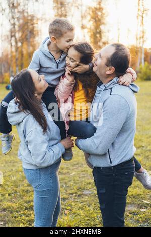 Les parents avec deux enfants passent du temps ensemble et s'amusent tout en marchant dans le parc à l'automne. Un enfant souriant et heureux. Famille heureuse ensemble Banque D'Images