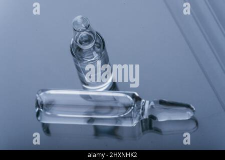 Flacon en ampoule médicale en verre pour injection. La médecine est un médicament blanc sec pénicilline poudre ou liquide avec de solution aqueuse dans l'ampulla. Gros plan. Flacons ampoule avec bouchon en aluminium sur fond gris. Banque D'Images