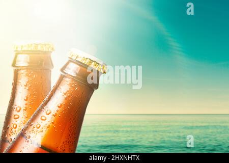 Gros plan sur le cou de deux bouteilles de verre humide de bière foncée sur le fond de l'océan et du ciel. Copier l'espace. Boissons alcoolisées sur vacati Banque D'Images