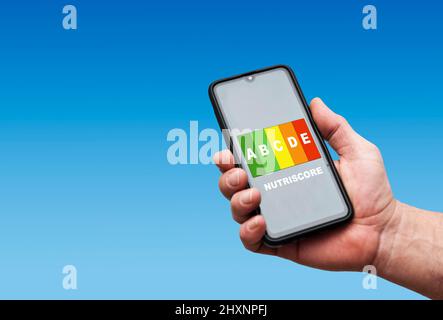 main tenant un smartphone portant une étiquette nutriscore à l'écran Banque D'Images