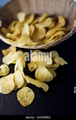 Croustillant de croustilles de pommes de terre dans un bol d'osier sur la vieille table de cuisine Banque D'Images