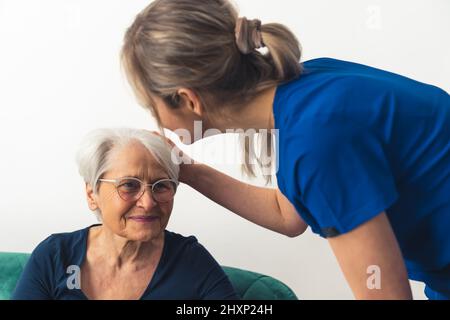 Une jeune infirmière de race blanche en uniforme bleu prend soin de la santé physique et mentale de sa patiente. Photo de haute qualité Banque D'Images