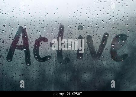 Le mot ACTIF est écrit sur le verre humide et brumeux de la pluie Banque D'Images