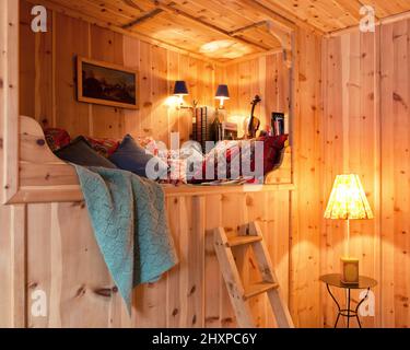 Alcôve lit de jour dans une salle lambrissée de maison de campagne autrichienne avec lampes, coussins, couverture et peinture Banque D'Images