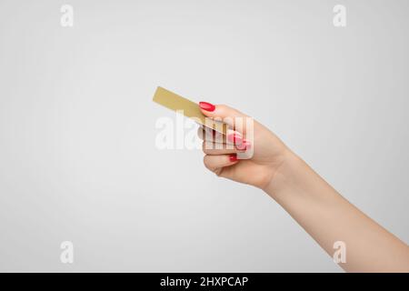 Carte de crédit ou de débit en plastique or dans la main d'une femme, vernis à ongles rouge Banque D'Images