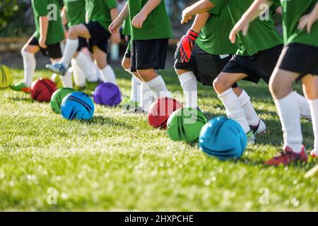 Rangée de joueurs de football pour enfants avec balles colorées sur le terrain d'entraînement. Enfants jouant au ballon de sport en plein air. Camp de football d'été pour l'âge élémentaire k Banque D'Images