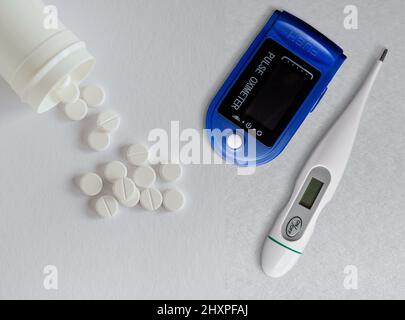 Oxymètre de pouls numérique , thermomètre et pilules blanches sur fond blanc. Vue de dessus avec espace de copie Banque D'Images