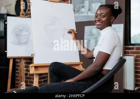 Portrait de l'étudiant souriant et dessin croquis sur toile pendant la classe d'art créatif. Jeune femme profitant de la leçon d'art développer de nouvelles compétences artistiques en studio de créativité. Résolutions du nouvel an Banque D'Images