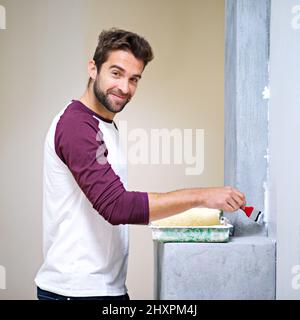 Faire du bricolage un jeu d'enfant. Photo d'un beau jeune homme peint un mur à l'intérieur. Banque D'Images