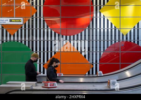 Tottenham court Road, Londres, Royaume-Uni. 14 mars 2022. Les personnes se rendant sur l'escalier mécanique de la station de métro Tottenham court Road avec un mur aux couleurs vives en arrière-plan à la pointe du matin. Crédit : Malcolm Park/Alay Live News Banque D'Images