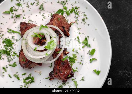 Côtes de porc grillées aux oignons et aux herbes, sur fond sombre Banque D'Images