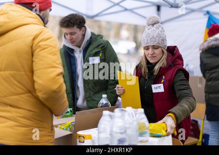 Volontaires distribuant de la nourriture et des boissons aux réfugiés à la frontière ukrainienne, concept d'aide humanitaire. Banque D'Images