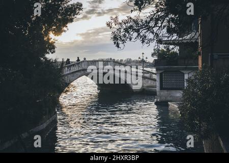 L'un des nombreux ponts sur un canal de Venise au coucher du soleil. Banque D'Images