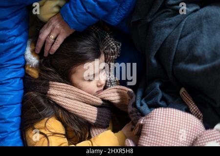 Les réfugiés ukrainiens de guerre dans un abri temporaire et centre d'aide, petite fille dormant sur les genoux de sa mère. Banque D'Images