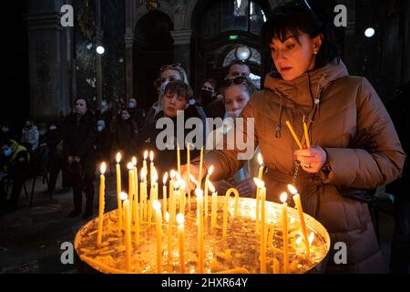 Lviv, Ukraine. 13th mars 2022. Une mère avec ses enfants a allumé des bougies pendant les prières à l'intérieur de l'Église. Des prières ont eu lieu dans l'église Saints Pierre et Paul Garrison, l'église historique de Lviv, pour pleurer les Ukrainiens qui sont morts et prier pour la paix. Crédit : SOPA Images Limited/Alamy Live News Banque D'Images