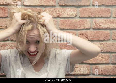 Une femme en dépression déchire ses cheveux. Problèmes des femmes, stress, problèmes. Banque D'Images