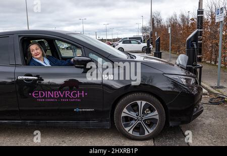 Ingliston Park & Ride, Édimbourg, Écosse, Royaume-Uni, 14 mars 2022. Ingliston Park & Ride batteries de chargement de voitures électriques : le responsable des transports et le conseiller municipal de la ville d'Édimbourg, Lesley MacInnes, voit comment les nouveaux chargeurs fonctionnent avec une voiture électrique du conseil municipal de la ville d'Édimbourg au parc et à la promenade. Quinze nouveaux chargeurs 7kwh ont été installés pour accueillir 30 véhicules électriques de plus dans le cadre du déploiement de 2,2m 000 £ du Conseil dans toute la ville. Banque D'Images