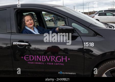 Ingliston Park & Ride, Édimbourg, Écosse, Royaume-Uni, 14 mars 2022. Ingliston Park & Ride batteries de chargement de voitures électriques : le responsable des transports et le conseiller municipal de la ville d'Édimbourg, Lesley MacInnes, voit comment les nouveaux chargeurs fonctionnent avec une voiture électrique du conseil municipal de la ville d'Édimbourg au parc et à la promenade. Quinze nouveaux chargeurs 7kwh ont été installés pour accueillir 30 véhicules électriques de plus dans le cadre du déploiement de 2,2m 000 £ du Conseil dans toute la ville. Banque D'Images