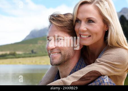 Regarder ensemble vers l'avenir. Photo d'un couple affectueux et mûr assis à côté d'un lac à la campagne. Banque D'Images