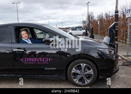 Ingliston Park & Ride, Édimbourg, Écosse, Royaume-Uni, 14 mars 2022. Ingliston Park & Ride batteries de chargement de voitures électriques : le responsable des transports et le conseiller municipal de la ville d'Édimbourg, Lesley MacInnes, voit comment les nouveaux chargeurs fonctionnent avec une voiture électrique du conseil municipal de la ville d'Édimbourg au parc et à la promenade. Quinze nouveaux chargeurs 7kwh ont été installés pour accueillir 30 véhicules électriques de plus dans le cadre du déploiement de 2,2m 000 £ du Conseil dans toute la ville. Banque D'Images