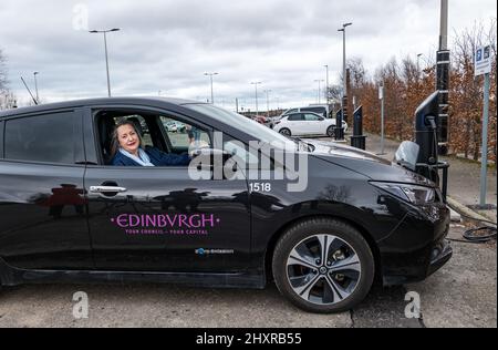 Ingliston Park & Ride, Édimbourg, Écosse, Royaume-Uni, 14 mars 2022. Ingliston Park & Ride batteries de chargement de voitures électriques : le responsable des transports et le conseiller municipal de la ville d'Édimbourg, Lesley MacInnes, voit comment les nouveaux chargeurs fonctionnent avec une voiture électrique du conseil municipal de la ville d'Édimbourg au parc et à la promenade. Quinze nouveaux chargeurs 7kwh ont été installés pour accueillir 30 véhicules électriques de plus dans le cadre du déploiement de 2,2m 000 £ du Conseil dans toute la ville. Banque D'Images