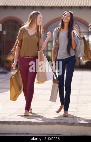 Temps de qualité. Deux jeunes femmes attirantes avec leurs sacs d'achats après une journée de thérapie au détail. Banque D'Images
