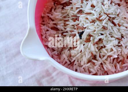 Cuisine et nourriture, riz long au jasmin brun et blanc non cuit, riz basmati ou riz au jasmin thaï sur une tasse à mesurer. Forte en vitamine B3, B6, B1 et B5. Banque D'Images