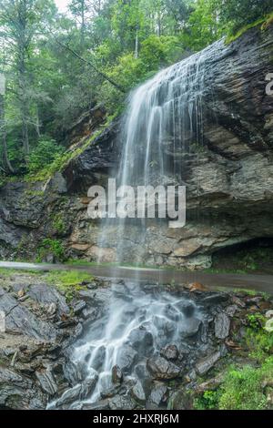 Une chute d'eau en bord de route qui passe au-dessus d'une falaise et d'une route qui est maintenant fermée, que vous pouvez marcher derrière les chutes qui s'éclatent vers les rochers et le ro Banque D'Images