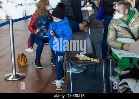 Ferrara, le 14 mars 2022. Un enfant joue avec une arme à feu tandis que les réfugiés ukrainiens de guerre ont la vaccination contre les covidés et des tests médicaux à Ferrara, en Italie. Credit: Filippo Rubin / Alamy Live News Banque D'Images