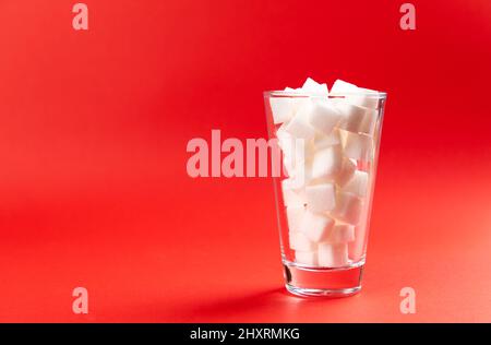 verre avec cubes de sucre sur fond rouge. Banque D'Images