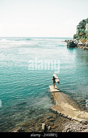 Belle vue d'une femme tenant une planche de surf sur une promenade près de la mer Banque D'Images