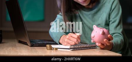 La jeune fille met son épargne dans une banque de porc. Banque D'Images