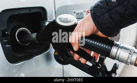 Gros plan de la main met la pompe à carburant dans la voiture Banque D'Images