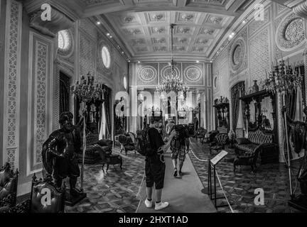 Photo en niveaux de gris des touristes prenant des photos dans la salle centrale du Palais national de Pena, Portugal Banque D'Images