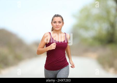 Vue avant portrait d'un coureur en train de courir vers l'appareil photo dans la montagne Banque D'Images
